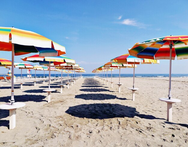 Multi colored umbrellas on beach against sky