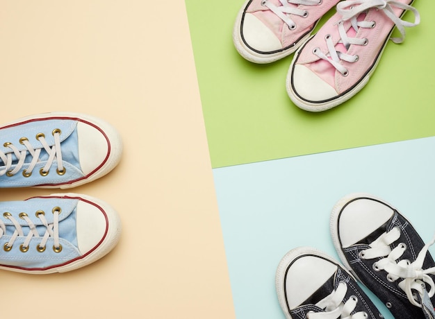 Photo multi-colored well-worn textile sneakers of different sizes on a green background top view