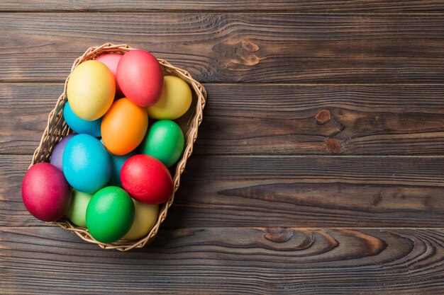 Multi colors Easter eggs in the woven basket on colored background Pastel color Easter eggs holiday concept with copy space