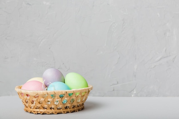 Multi colors Easter eggs in the woven basket on colored background Pastel color Easter eggs holiday concept with copy space