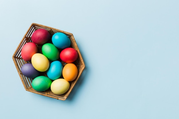 Multi colors Easter eggs in the woven basket on colored background Pastel color Easter eggs holiday concept with copy space