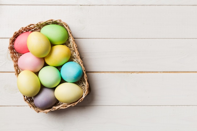 Multi colors Easter eggs in the woven basket on colored background Pastel color Easter eggs holiday concept with copy space