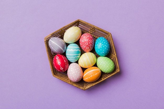 Разноцветные пасхальные яйца в плетеной корзине на цветном фоне Пастельные цвета Пасхальные яйца концепция праздника с копией пространства