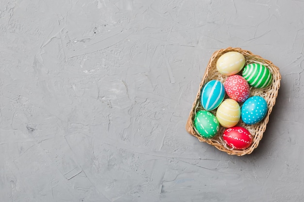 Multi colors Easter eggs in the woven basket on colored background Pastel color Easter eggs holiday concept with copy space