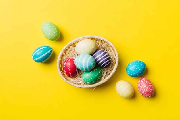 Multi colors Easter eggs in the woven basket on colored background Pastel color Easter eggs holiday concept with copy space