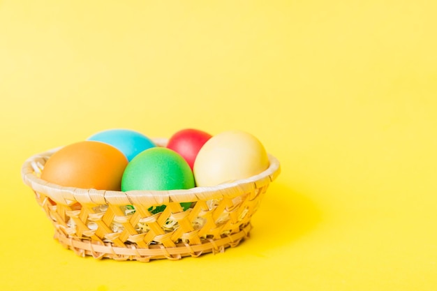 Multi colors Easter eggs in the woven basket on colored background Pastel color Easter eggs holiday concept with copy space