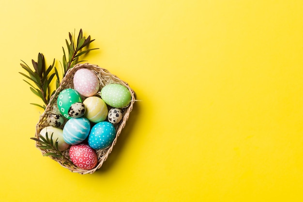 Разноцветные пасхальные яйца в плетеной корзине на цветном фоне Пастельные цвета Пасхальные яйца концепция праздника с копией пространства