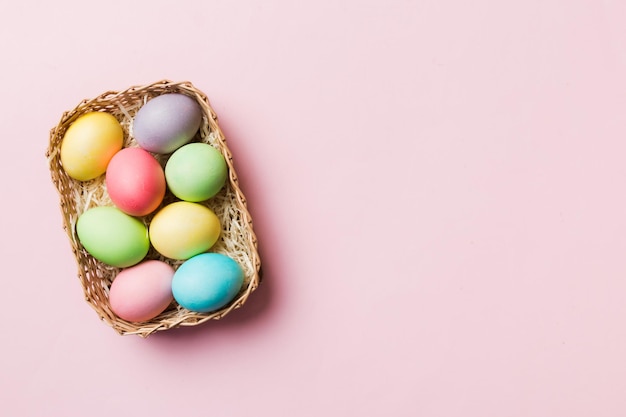 Multi colors Easter eggs in the woven basket on colored background Pastel color Easter eggs holiday concept with copy space