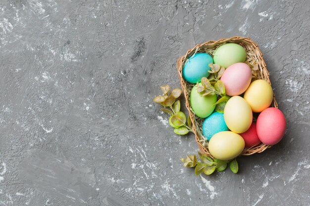 Multi colors Easter eggs in the woven basket on colored background Pastel color Easter eggs holiday concept with copy space