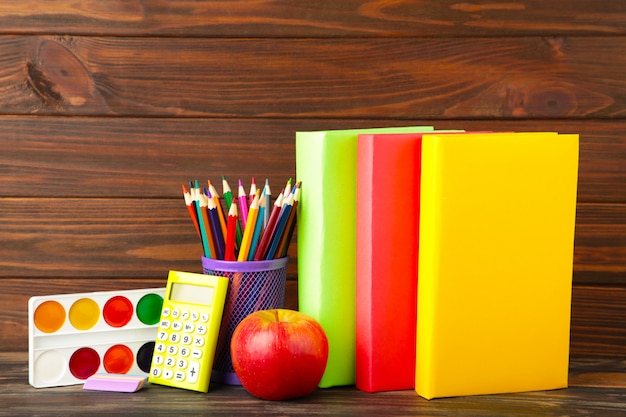 Multi libri di scuola e cancelleria colorati sulla parete di legno marrone