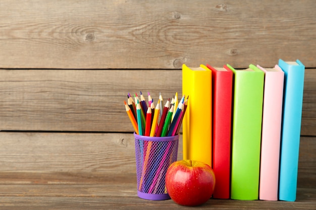 Multi coloured school books and stationery on grey wooden background