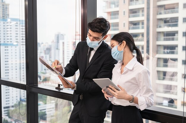 Multi ethnic business colleague wearing face mask discussing and consulting in new normal office at business district While pandemic of Coronavirus Covid