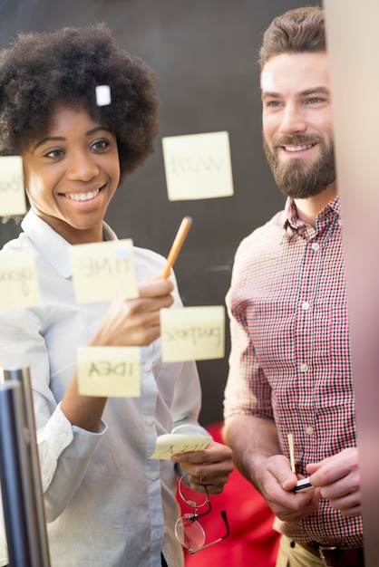 Photo multi ethnic coworkers working together with stickers on the transparent door at the office