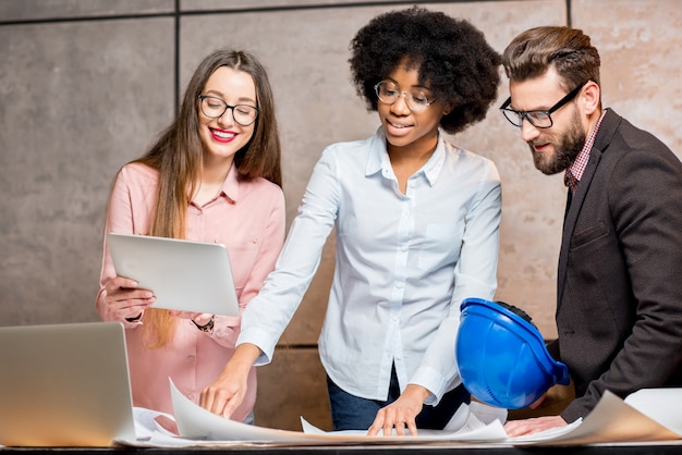 Foto gruppo multietnico di architetti o designer che lavorano insieme sui piani architettonici in ufficio