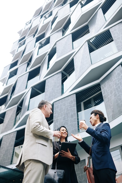 Multi-ethnic group of business people standing outside the modern office building and discussing ideas