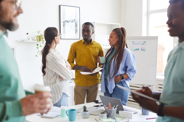 Multi-ethnic group of creative business people chatting during break in conference room