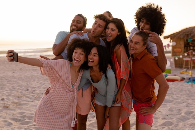 A multi-ethnic group of friends enjoying their time together, holding a smartphone, taking a selfie together