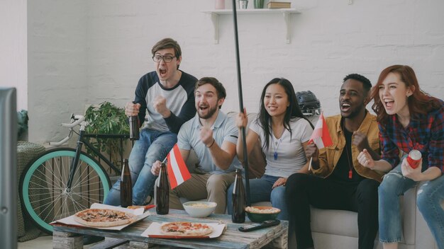 Multi ethnic group of friends sports fans with Austrian national flags watching hockey championship