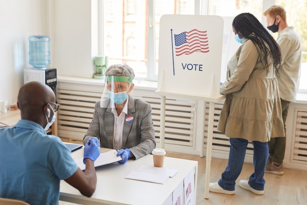 写真 パンデミック後の選挙日に投票所でマスクとppe投票を行う多民族グループ、コピースペース