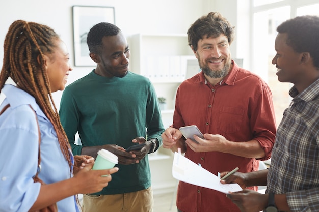 Photo multi-ethnic group of people dressed in casual wear and smiling cheerfully while discussing work standing in office