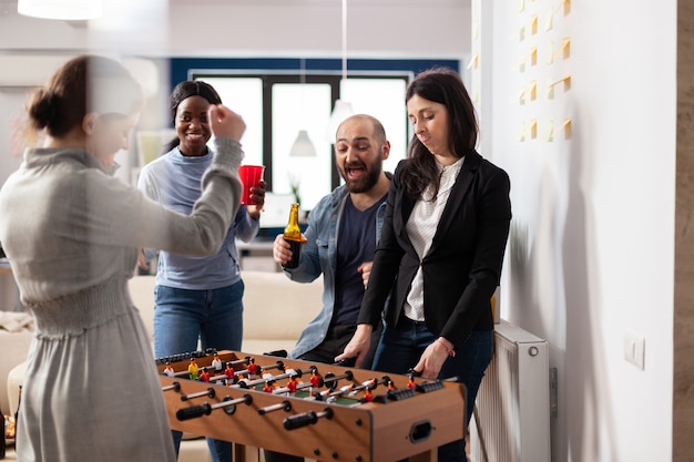 Multi ethnic group of people playing at foosball table