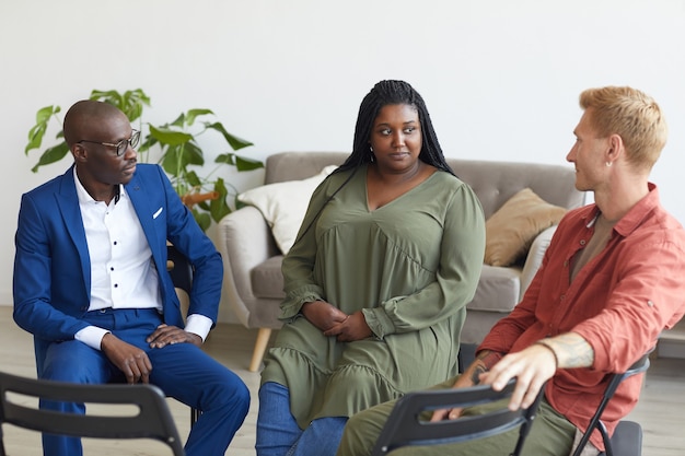 Photo multi-ethnic group of people sitting in circle during support group meeting and discussing issues, copy space