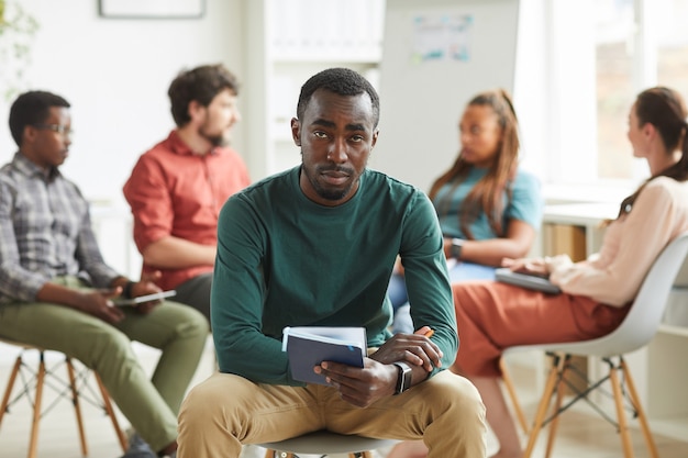 Multi-ethnic group of people sitting in circle while discussing business project in office