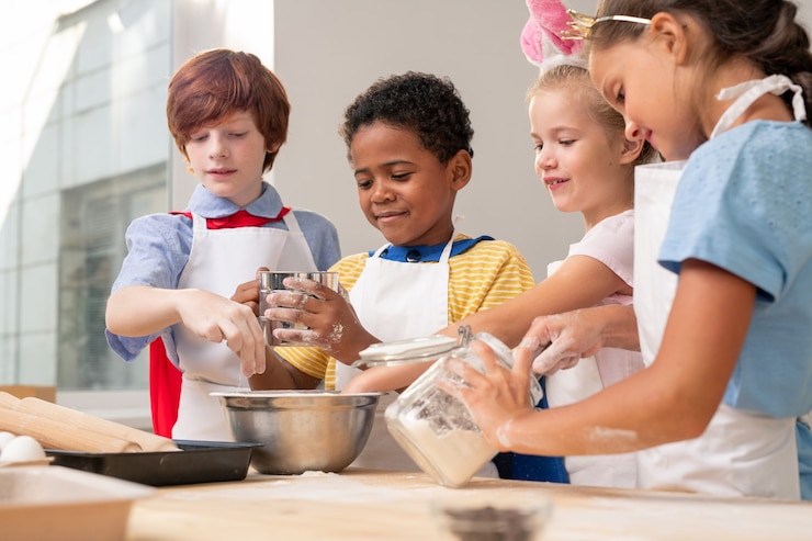 Photo multi-ethnic kids wearing aprons looking at each other while discussing festive menu while baking cookies