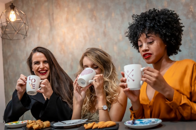 コーヒーを飲んでいる3つのガールフレンドの多民族のライフスタイル