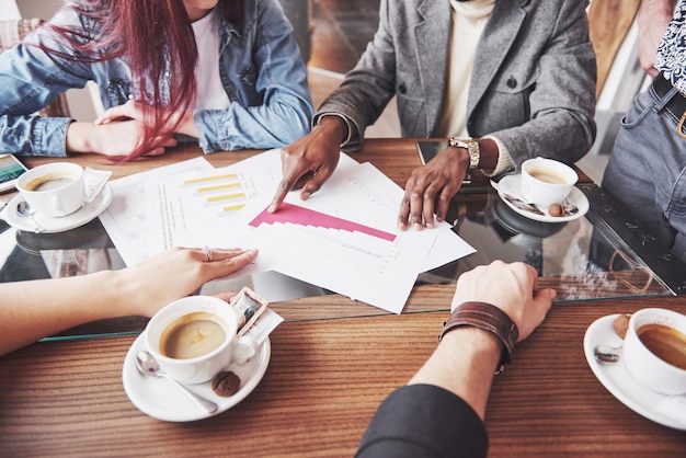 Multi ethnic people entrepreneur, small business concept. Woman showing coworkers something on laptop computer as they gather around a conference table