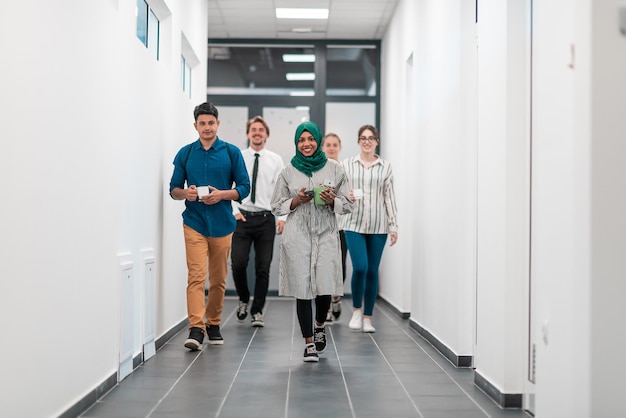 Multi-ethnic startup business team walking through the hallway\
of the building while coming back from a coffee break. high-quality\
photo