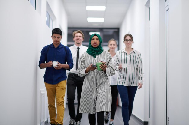 multi-ethnic startup business team walking through the hallway of the building while coming back from a coffee break