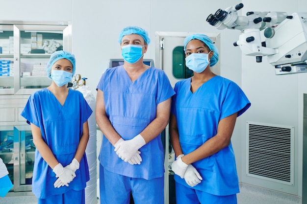 Multi-ethnic surgical team in scrubs, medical masks and disposable caps