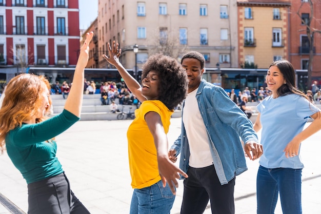 Giovani amici multietnici che ballano in una piazza della città divertendosi insieme in città