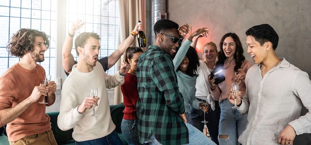 Foto amici giovani multietnici che fanno una festa a casa insieme persone divertenti e diverse che si divertono a ballare e cantare nel soggiorno durante una festa cool concetto di stile di vita giovanile filtro luminoso