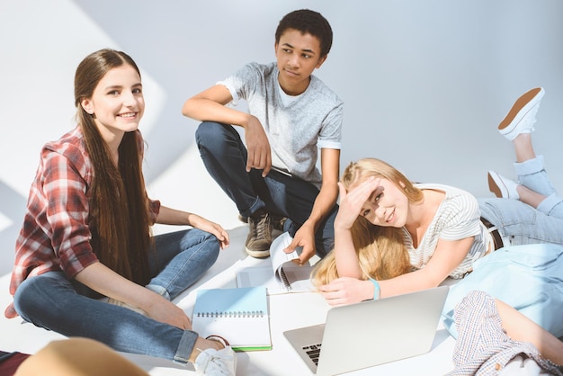 Foto multi-etnisch lachende tieners die laptop samen op wit gebruiken