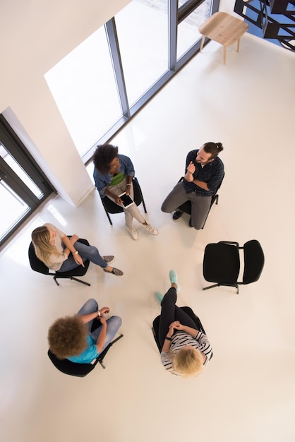 Multi-etnisch opstartend businessteam bij het ontmoeten in modern, helder kantoorinterieur brainstormen, werken aan laptop en tabletcomputer bovenaanzicht