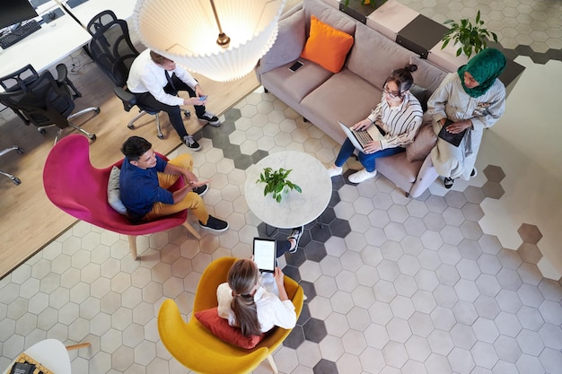Multi-etnisch opstartend businessteam met brainstorming in de ontspanningsruimte van een modern kantoorinterieur dat werkt op een laptop en tabletcomputer