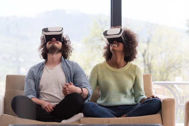 Foto multi-etnisch paar met behulp van virtual reality-headset in de woonkamer thuis mensen die een spel spelen met nieuwe trends-technologie