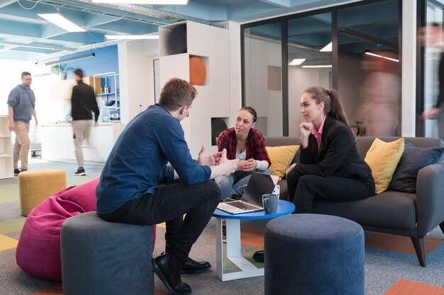 Multi-etnisch startend zakelijk team op bijeenkomst in een modern, helder open ruimte coworking-kantoor. Brainstormen, werken op laptop. Groep collega's die rondlopen in bewegingsonscherpte.