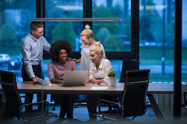 Multi-etnisch startend zakelijk team over ontmoeting in moderne nachtelijke kantoorinterieur brainstormen, werkend op laptop