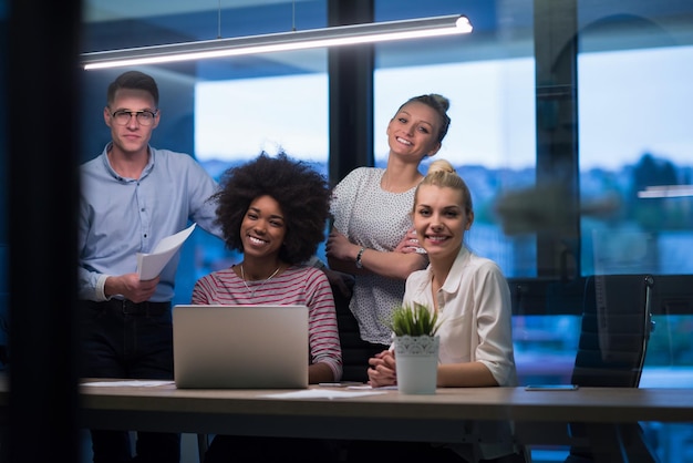 Multi-etnisch startend zakelijk team over ontmoeting in moderne nachtelijke kantoorinterieur brainstormen, werkend op laptop