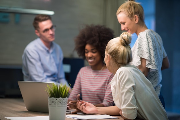 Multi-etnisch startend zakelijk team over ontmoeting in moderne nachtelijke kantoorinterieur brainstormen, werkend op laptop