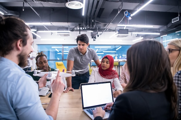 multi-etnisch startup business-team dat een nieuw businessplan bespreekt, werkt op een laptop en tablet terwijl je leert over drone-technologie voor nieuwe zakelijke vooruitgang