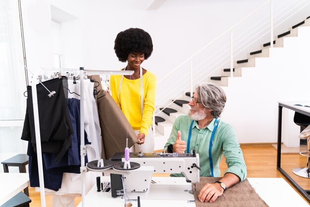 Multi-etnisch team van modeontwerpers werken in een kledingstart-up workshop - Multiraciale groep stylisten, kleermakers en kleermakers werken aan een nieuwe collectie