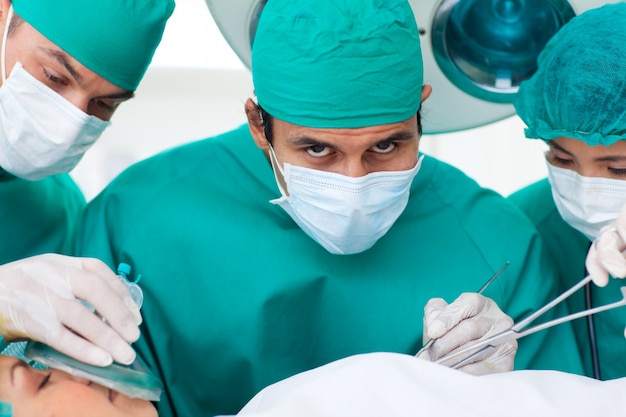 Multi-etnische chirurgen dichtbij patiënt die op operatielijst liggen
