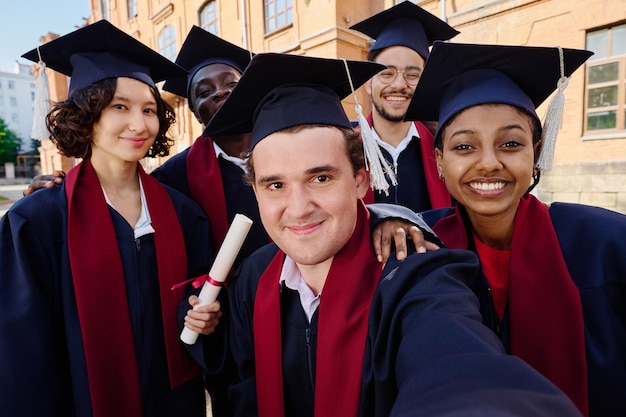 Multi-etnische groep afgestudeerde studenten die selfie portret buitenshuis maken