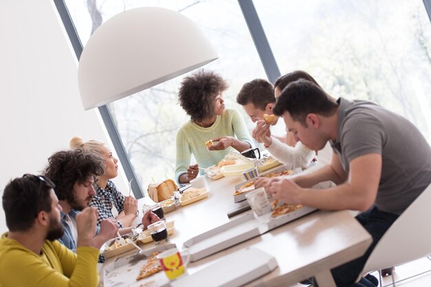 multi-etnische groep gelukkige vrienden die tijd doorbrengen samen met eten en frisdrank, thuis eten concept