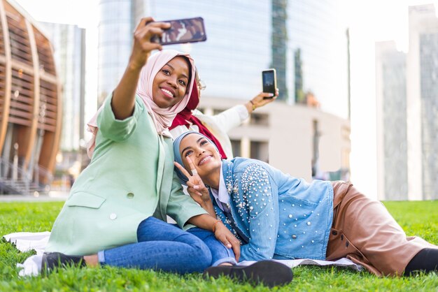 multi-etnische groep moslimmeisjes die vrijetijdskleding en traditionele hijab-binding buitenshuis dragen