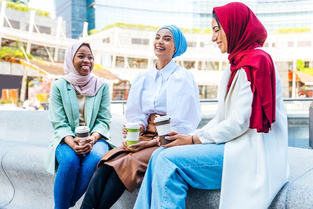 Multi-etnische groep moslimmeisjes die vrijetijdskleding en traditionele hijab-binding dragen en buiten plezier hebben - 3 arabische jonge meisjes